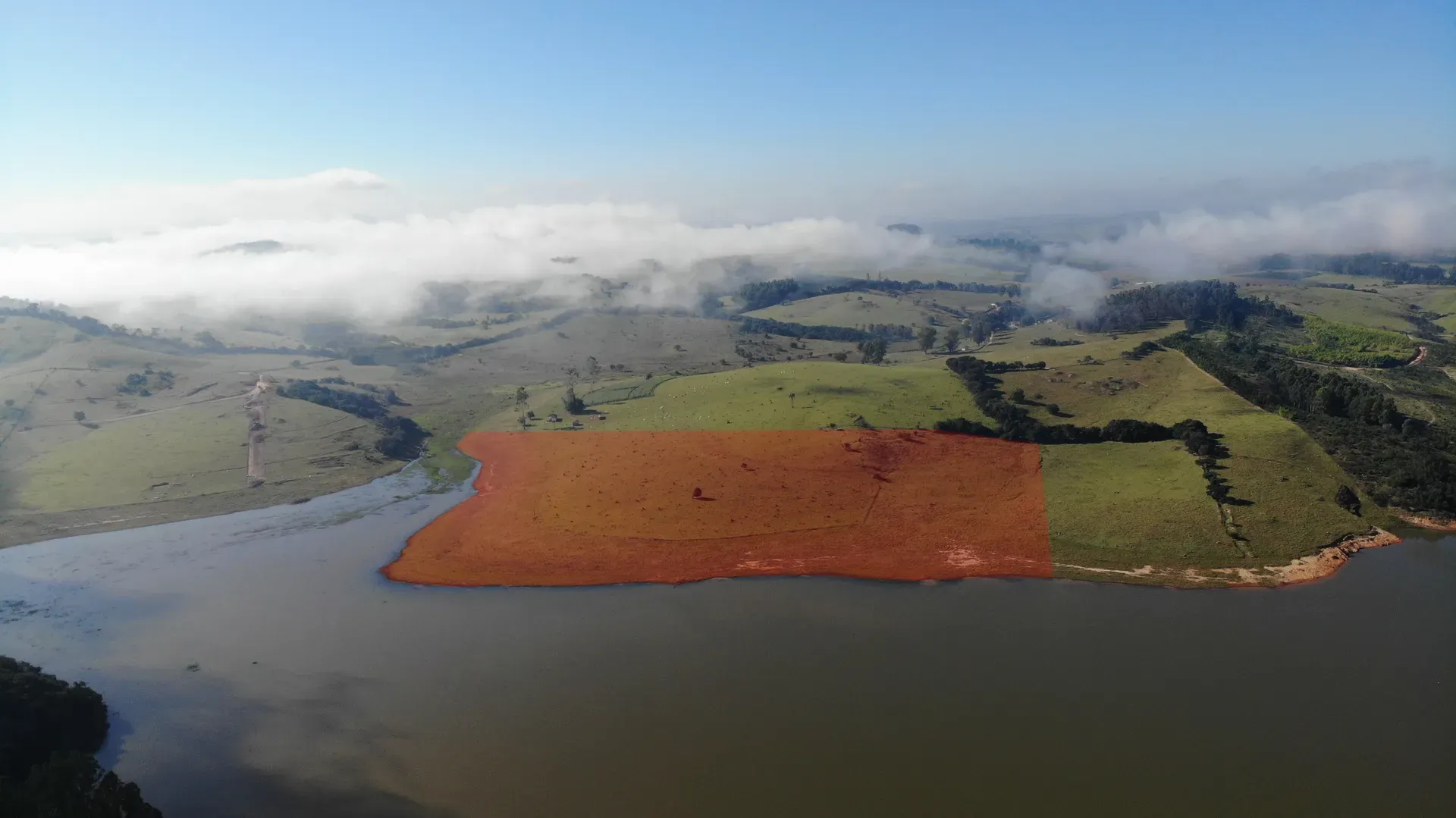Vista aérea da Fazenda Coelhos com a área da propriedade demarcada na frente d’água, às margens do lago, entre pastos e morros do Sul de Minas