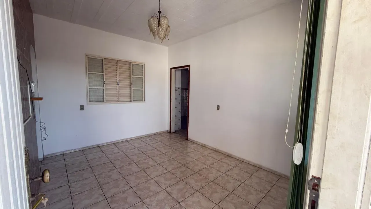 Sala da Casa do Lourdes, ampla e iluminada, com lustre, janela para a rua e piso cerâmico