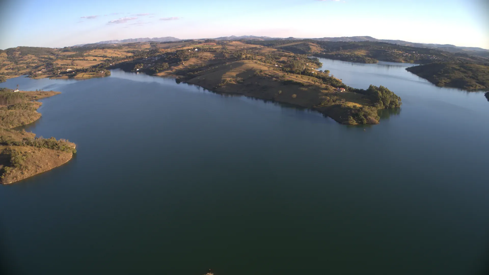 Aérea ampla da Represa do Funil mostrando braços do reservatório, ilhas e a cordilheira ao horizonte — contexto geográfico do condomínio
