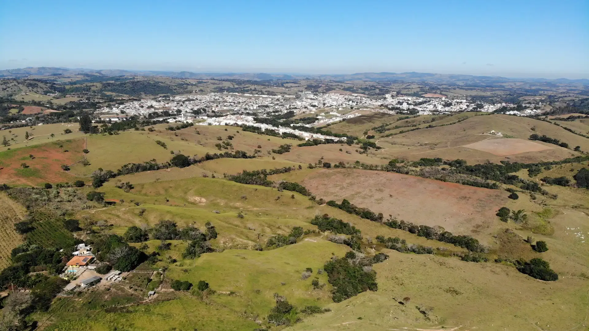 Pastagens da Fazenda Cachoeirinha em primeiro plano e a cidade de Perdões ao centro, entre os morros do Sul de Minas
