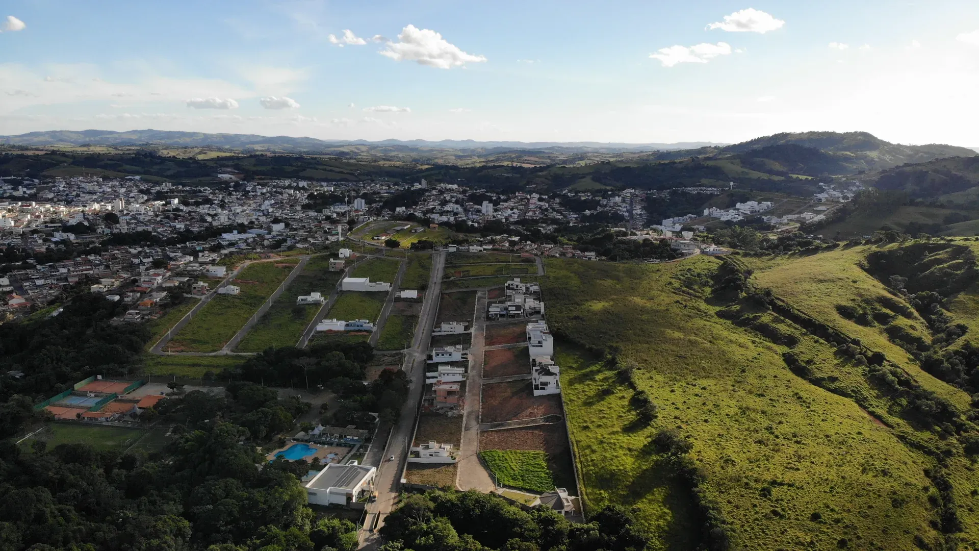 Aérea do conjunto urbano de Perdões com o Gran Ville à esquerda, cidade ao centro e cordilheira da serra ao fundo em luz de fim de tarde