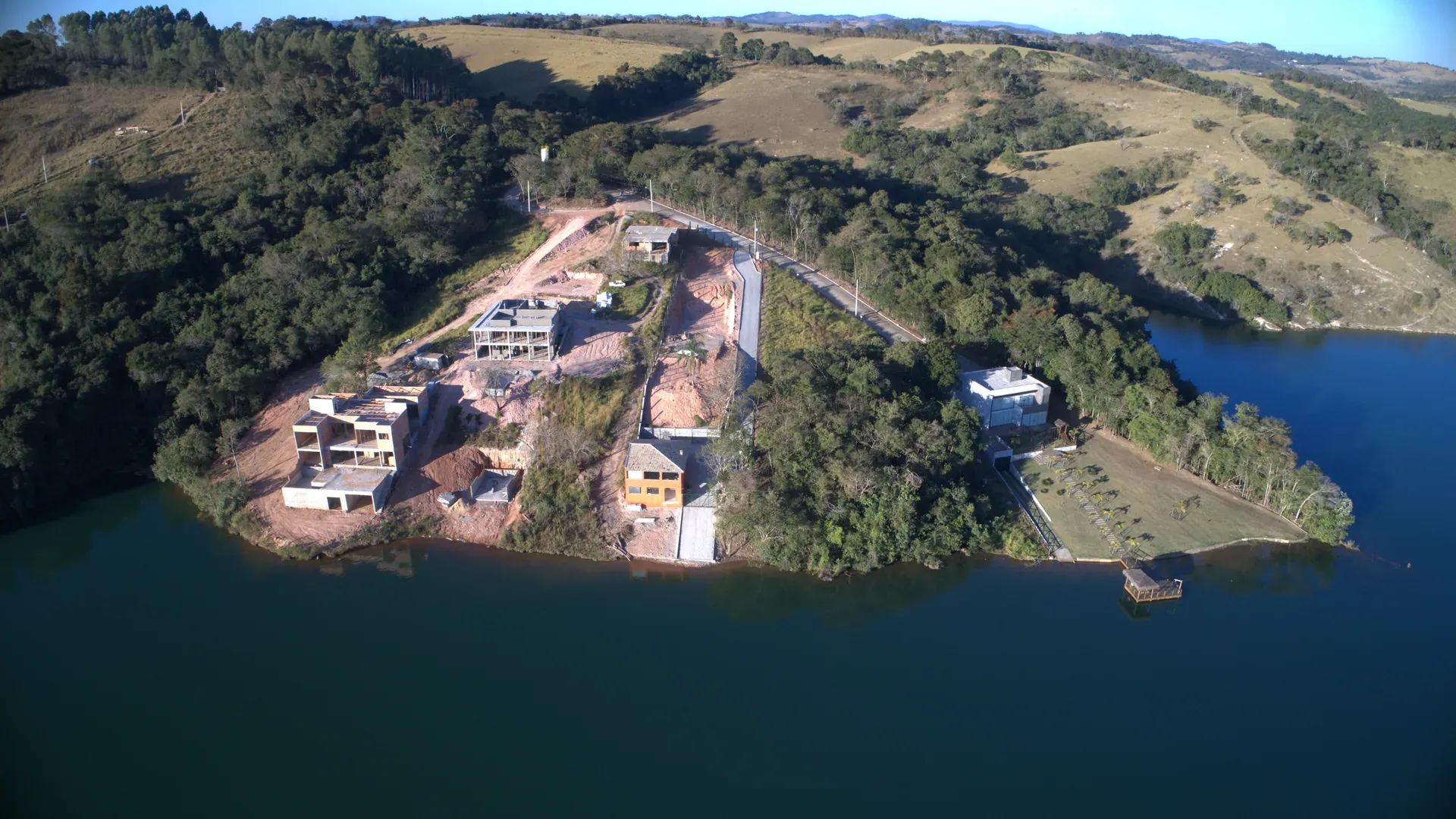 Aérea mais próxima da península do Estância do Funil com casas em diferentes fases de construção e o lago contornando o terreno
