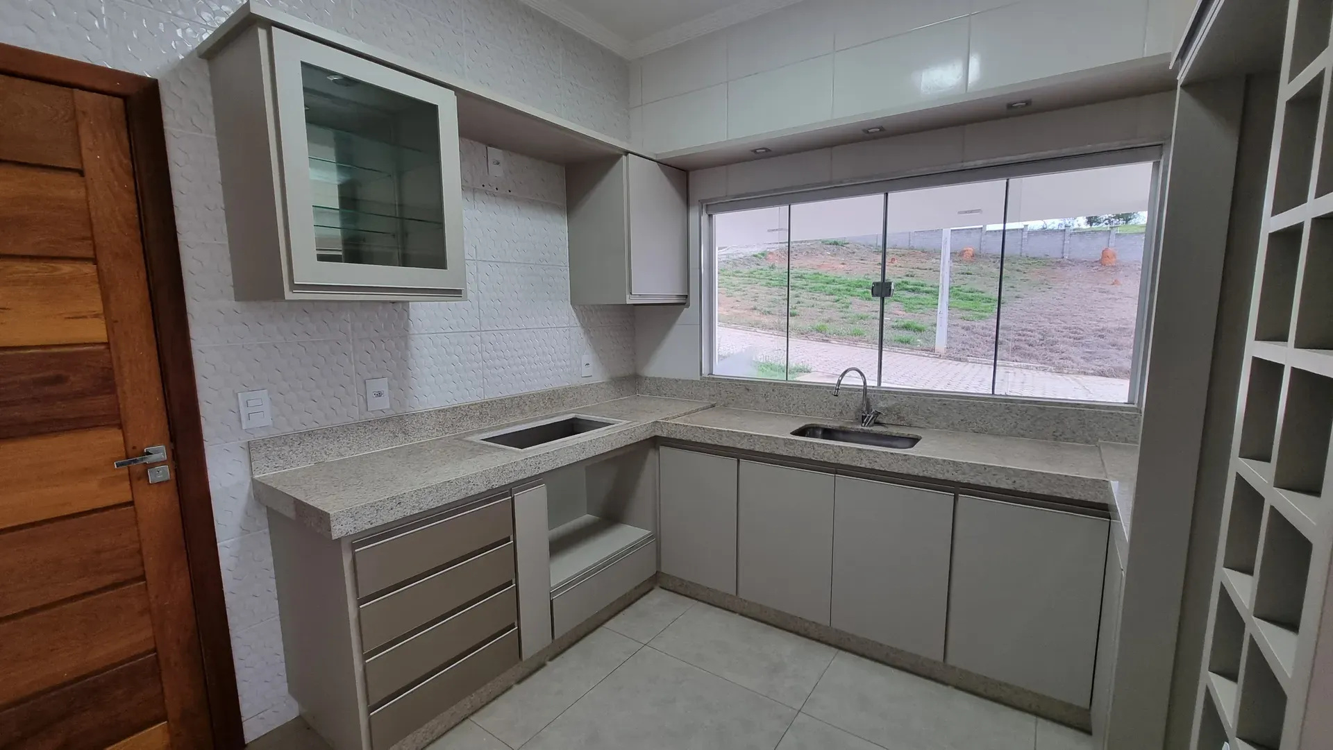 Cozinha da Casa do Gran Ville com bancada de granito, armários planejados e ampla janela para o quintal