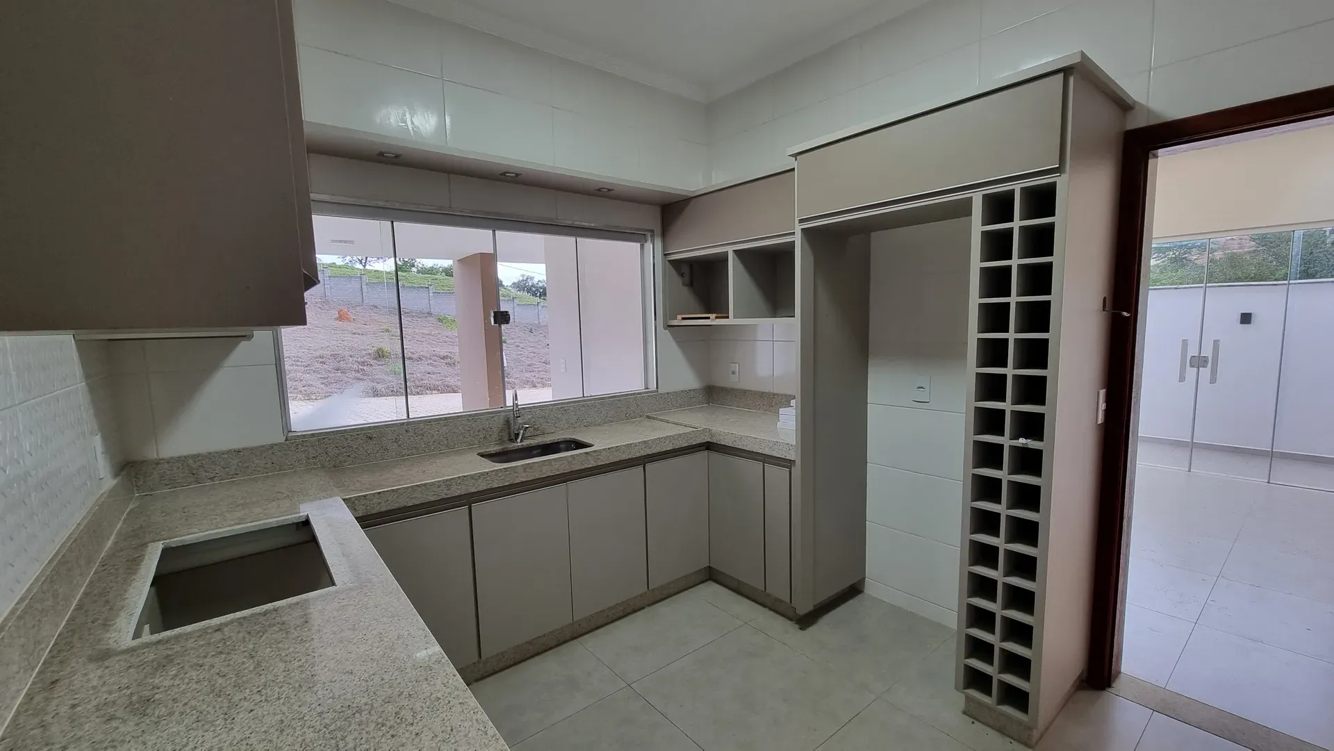 Cozinha da Casa do Gran Ville com armários planejados, adega embutida e cuba na bancada de granito