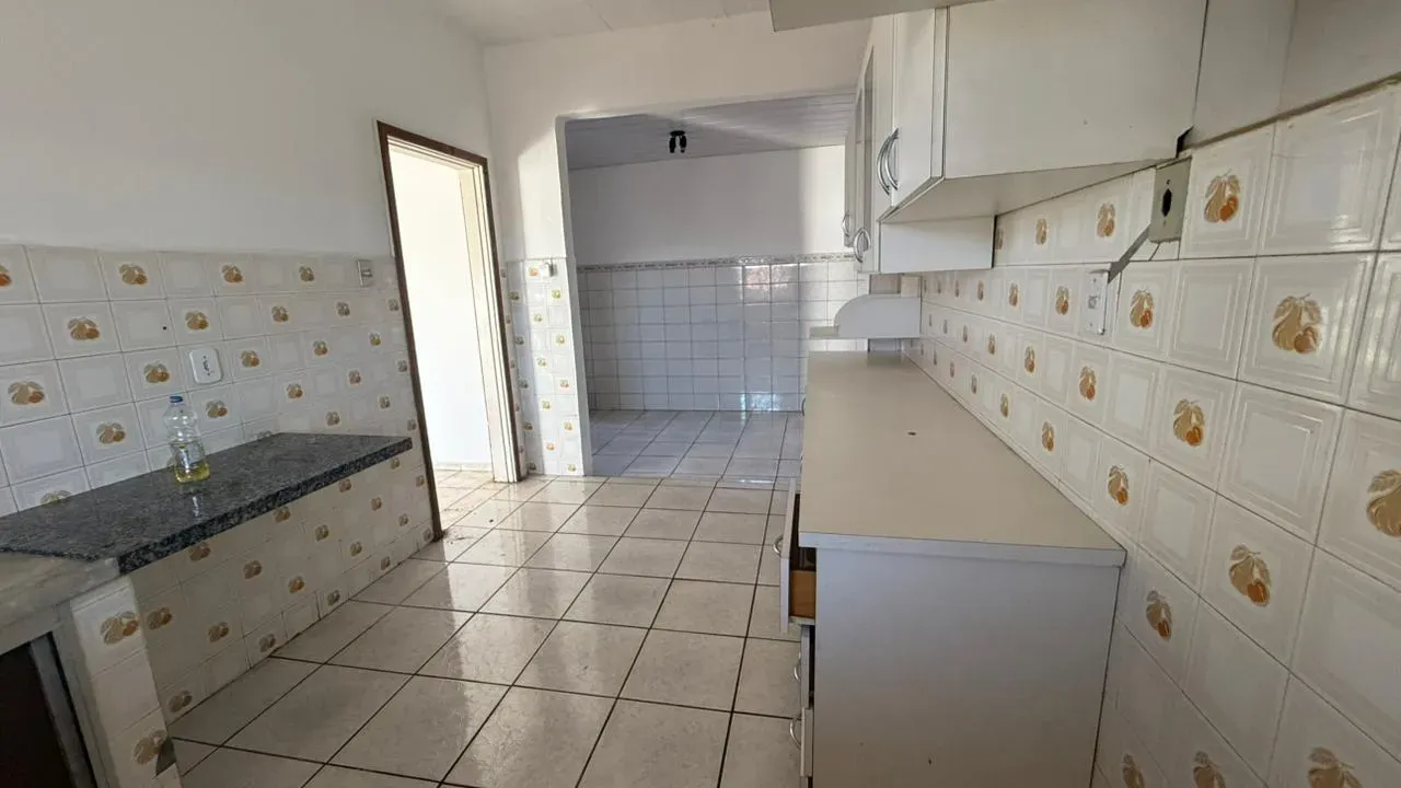 Cozinha da Casa do Lourdes com bancada de granito, armários e revestimento cerâmico nas paredes
