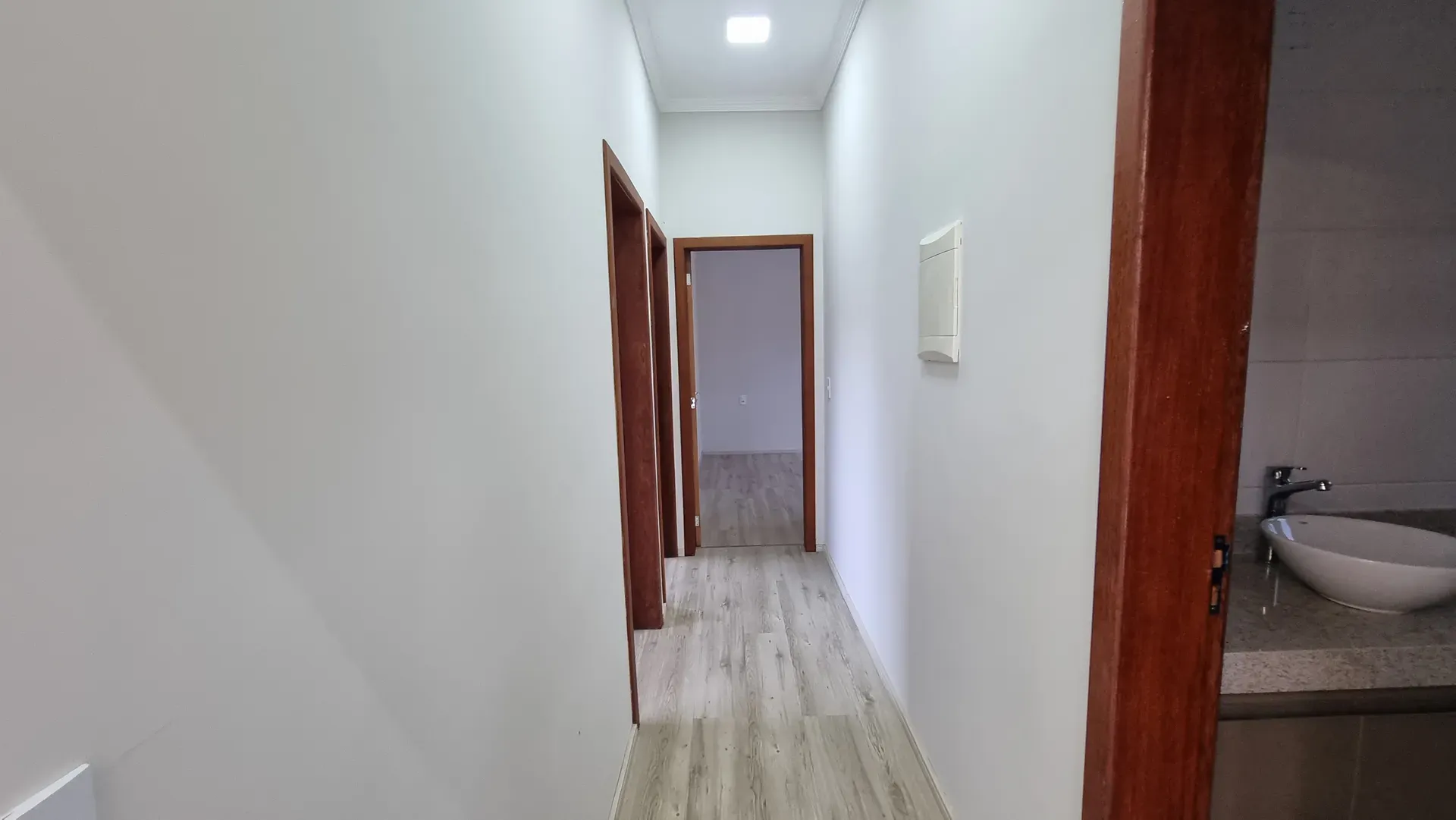 Corredor de circulação da Casa do Gran Ville, com piso amadeirado e acesso aos quartos e ao banheiro