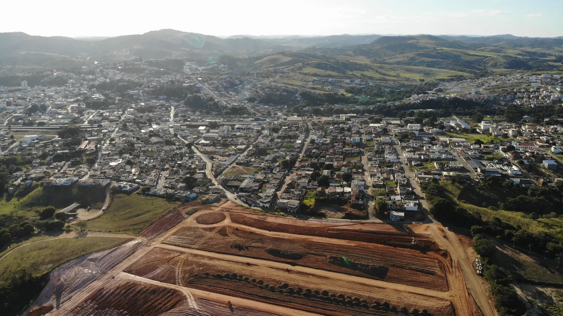 Vista aérea do Portal da Serra sob a luz dourada do fim de tarde, com a cidade de Perdões dominando o horizonte