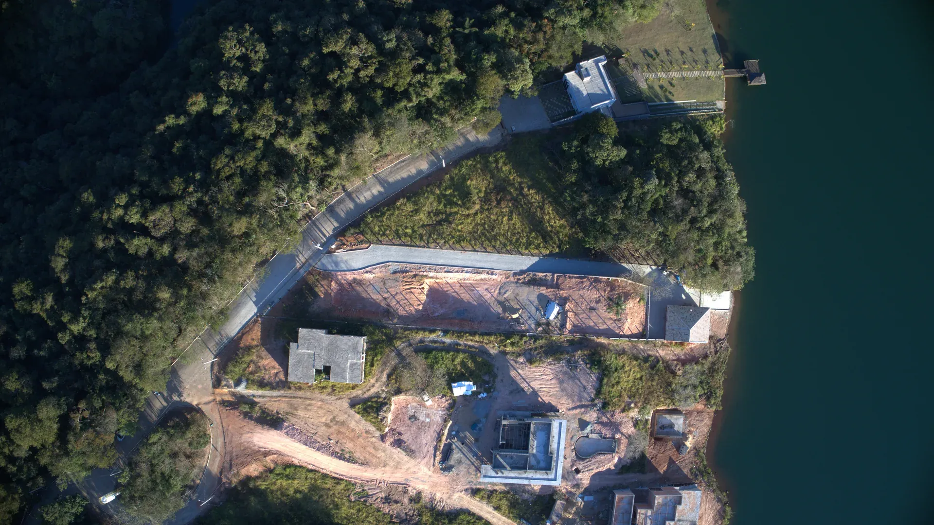 Vista top-down do masterplan do condomínio mostrando o traçado das vias, lotes e o entorno aquático