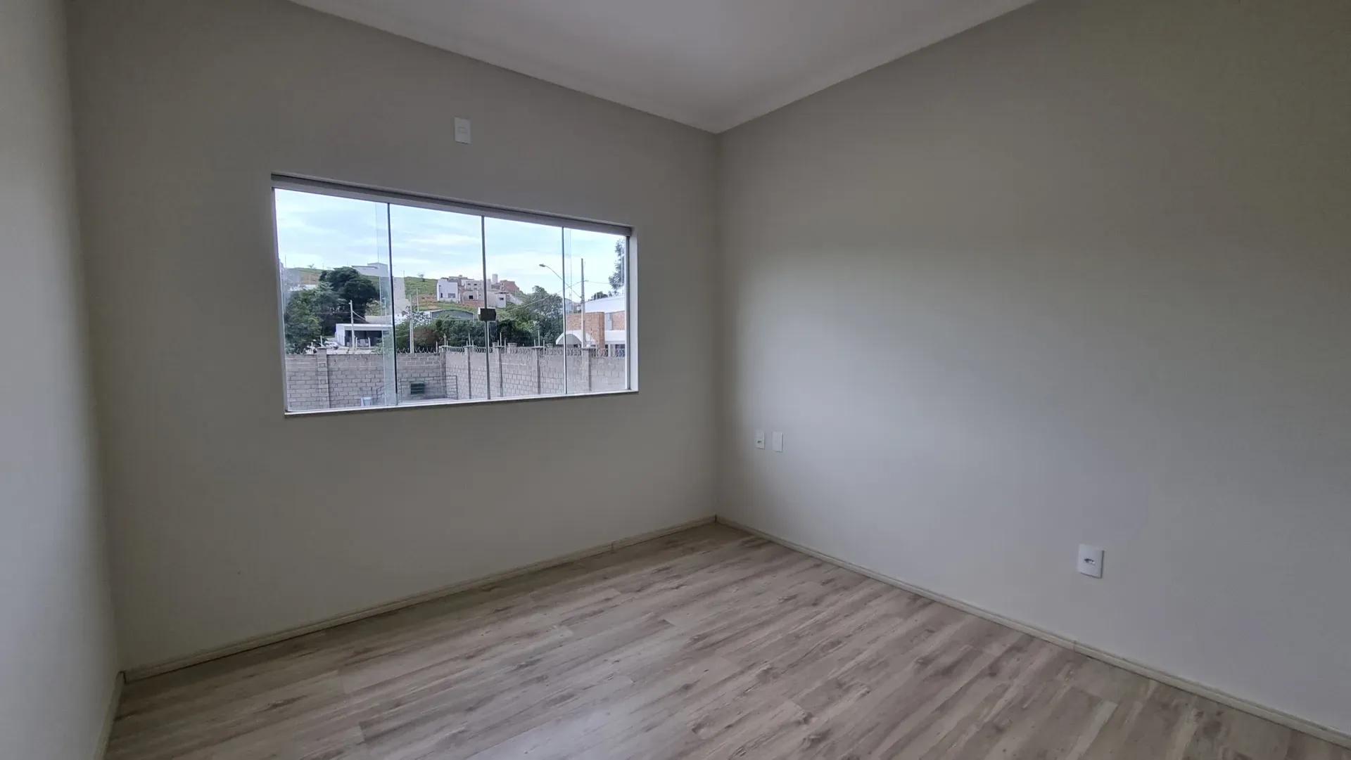 Quarto da Casa do Gran Ville com piso amadeirado e ampla janela de vidro
