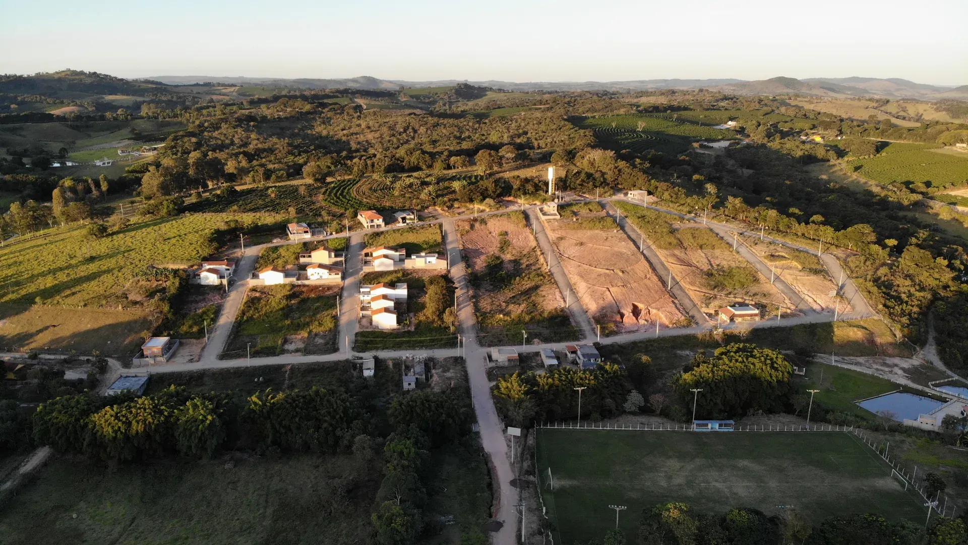 Vista aérea panorâmica do Residencial Bela Vista com o entorno verde do Sul de Minas, cafezais e mata nativa ao redor do loteamento