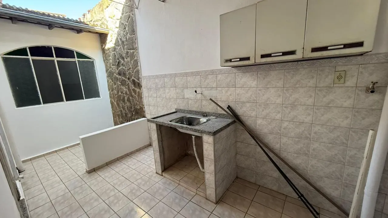 Área de serviço da Casa do Lourdes, com tanque, armários aéreos e parede de pedra