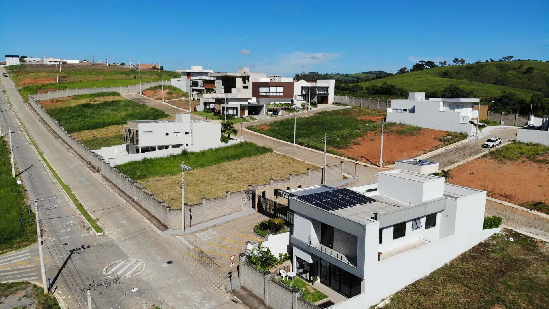 Rua interna do Gran Ville com casa moderna em destaque, residências de alto padrão alinhadas e a serra ao fundo