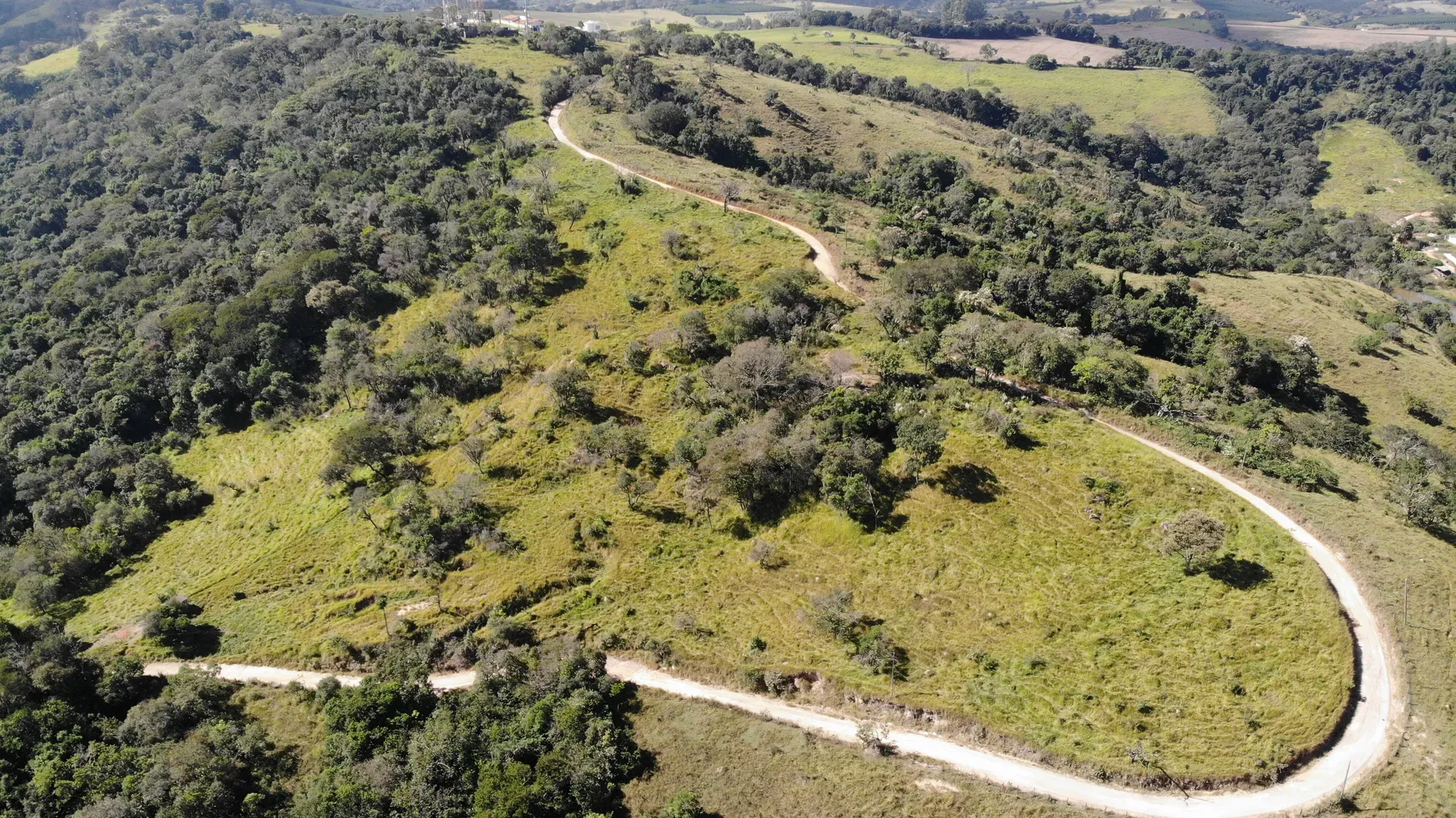 Terreno Inhame arborizado, com estradas de acesso e o vale cultivado do entorno ao fundo