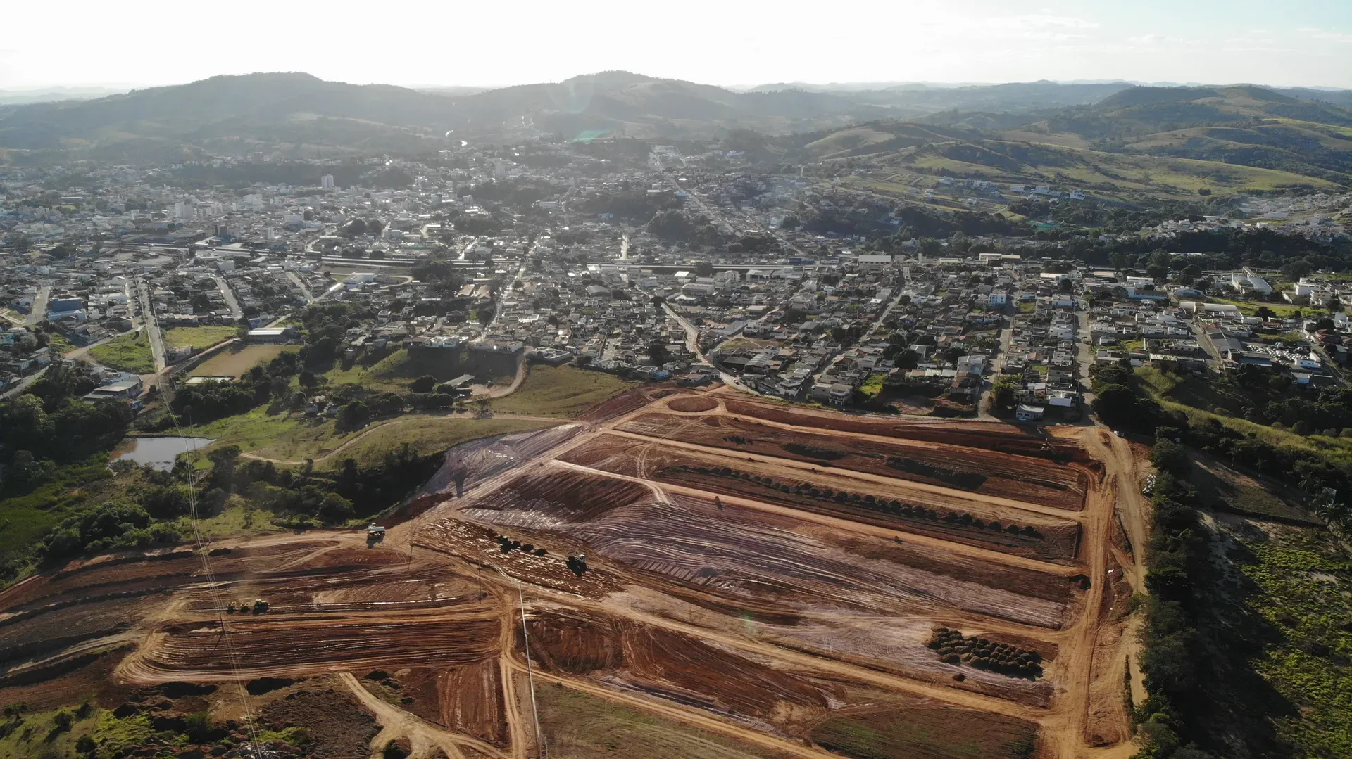 Vista aérea ampla do loteamento Portal da Serra em obras, com Perdões e a serra do Sul de Minas