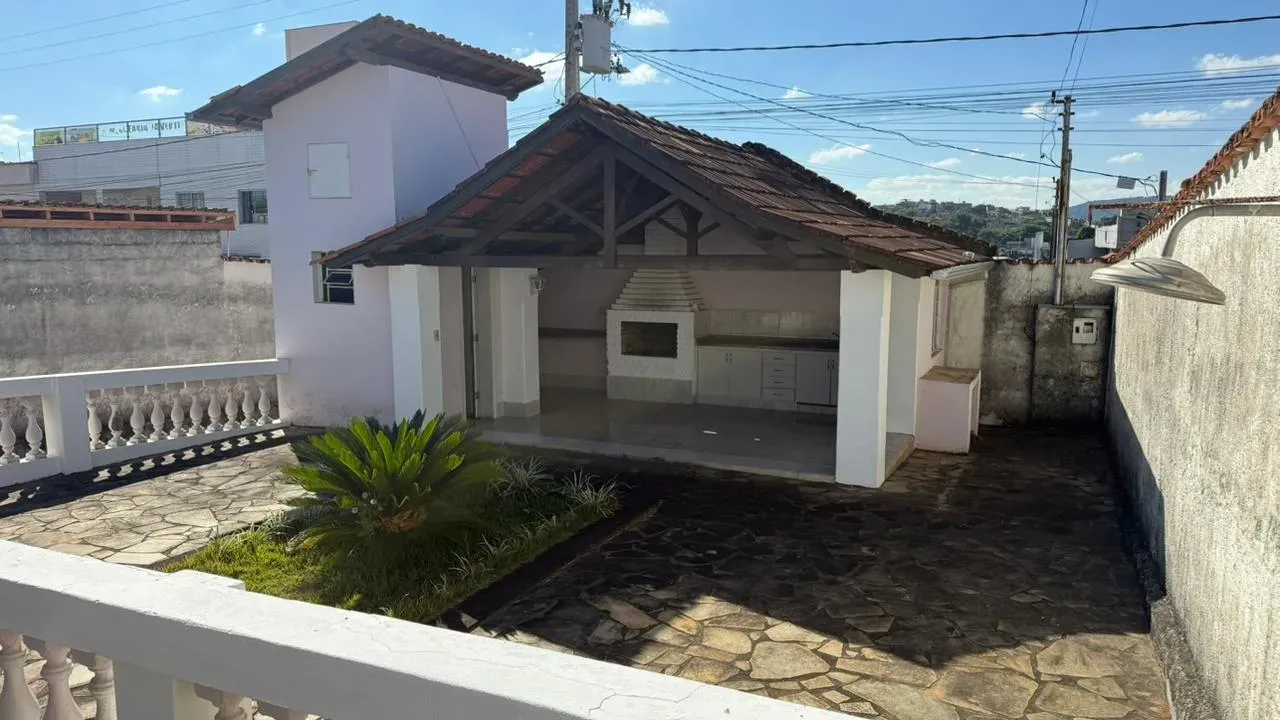 Área gourmet da Casa do Lourdes, com churrasqueira, bancada com pia e amplo terraço em pedra
