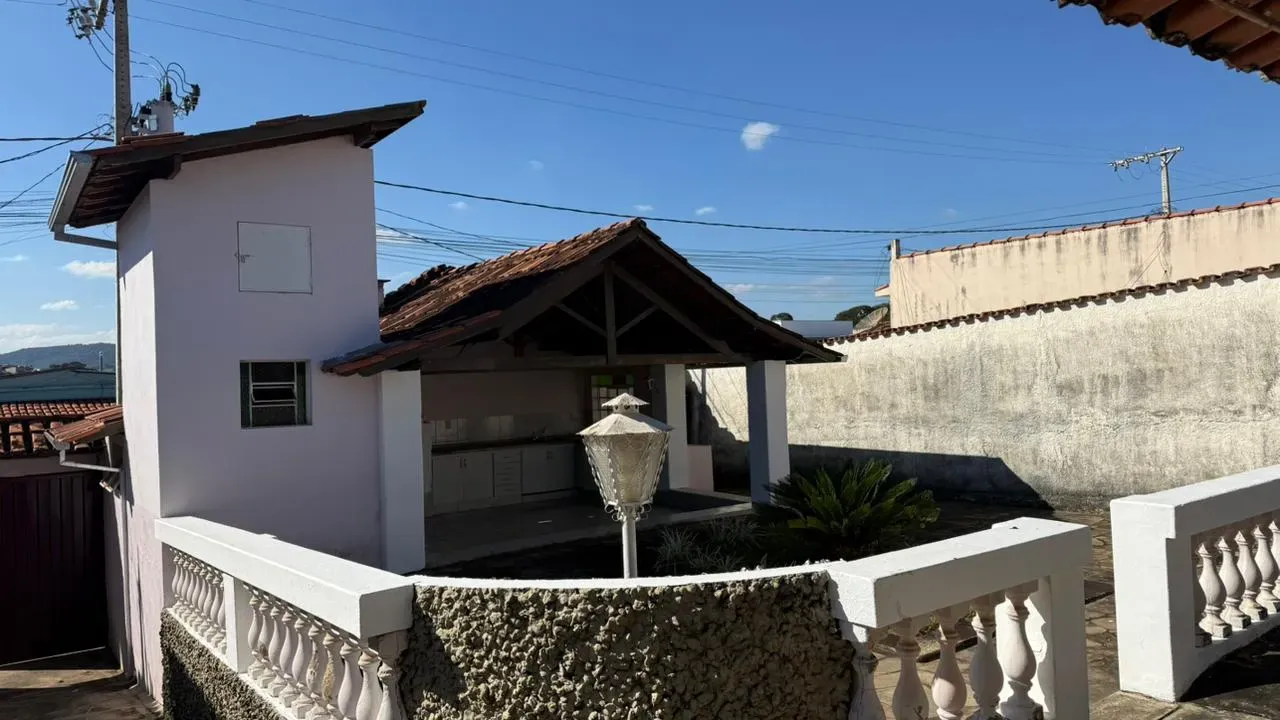 Área gourmet e quintal da Casa do Lourdes, com churrasqueira coberta, balaustrada e poste de iluminação