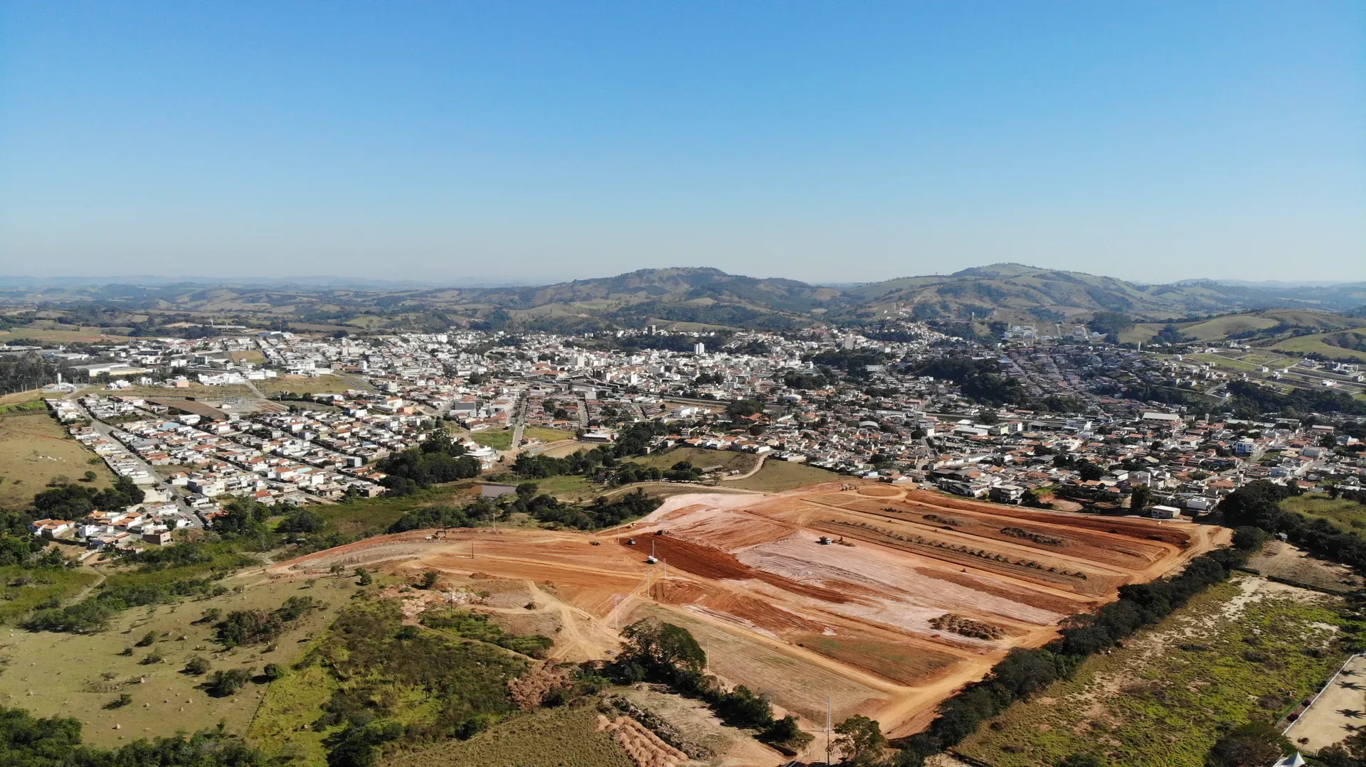 Vista aérea panorâmica do Portal da Serra com o loteamento em obras e a serra do Sul de Minas ao fundo