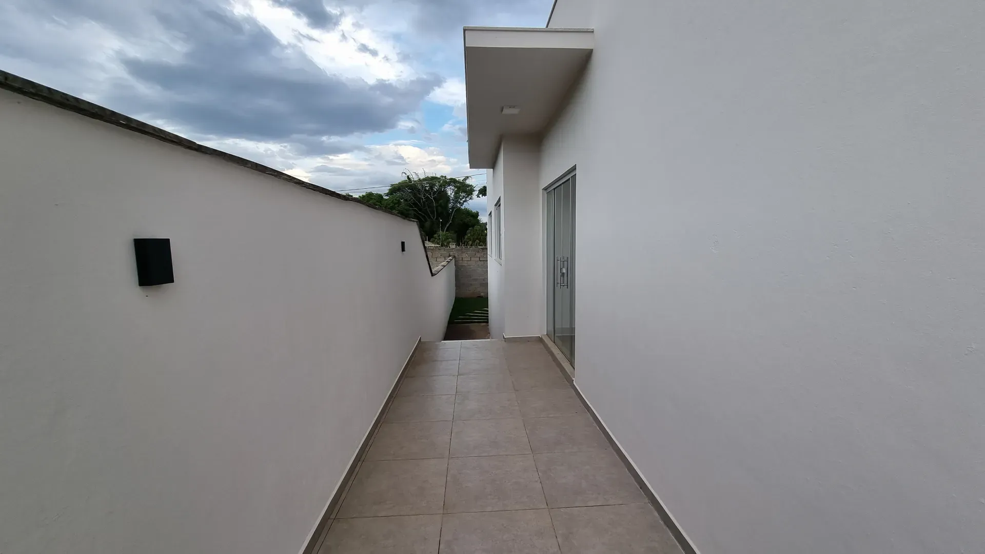 Corredor lateral externo da Casa do Gran Ville, com piso de porcelanato e acesso ao quintal