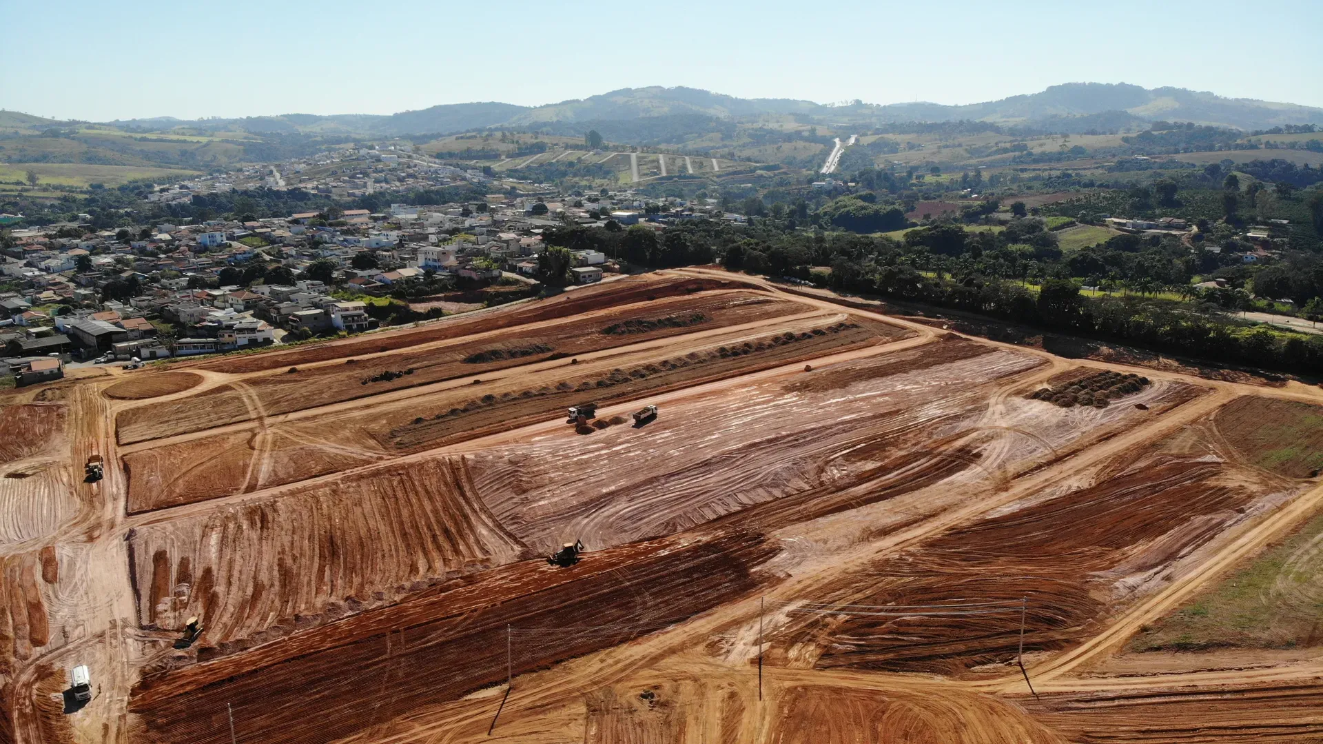 Aérea das frentes de obra do Portal da Serra, com os platôs do loteamento e a serra ao fundo