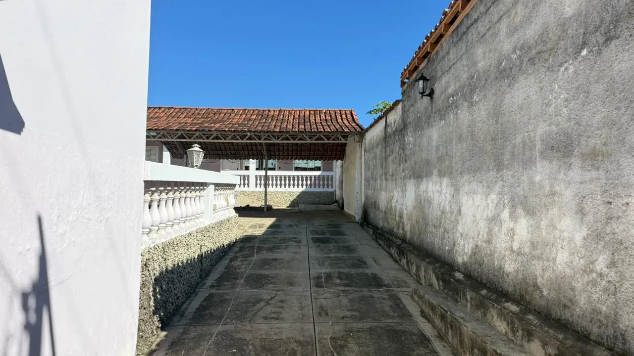 Quintal lateral da Casa do Lourdes, com piso de concreto, balaustrada e muro de divisa