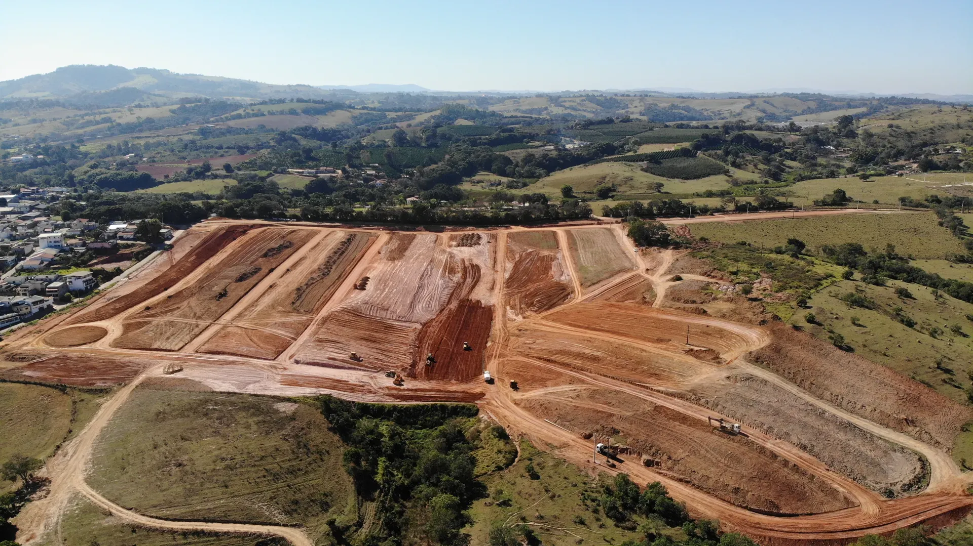 Aérea do Portal da Serra em terraplenagem cercado pelo entorno verde do Sul de Minas, com a serra ao fundo