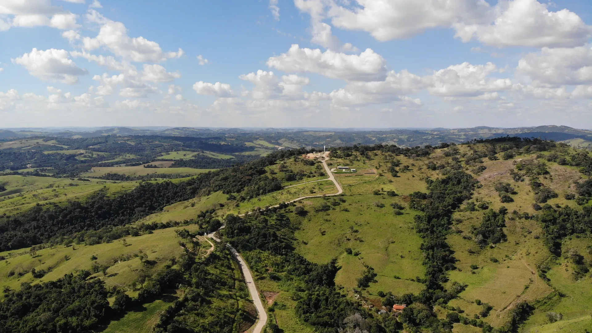 Vista aérea panorâmica da serra de Perdões/MG onde fica o Condomínio Estância da Serra, com camadas de morros, vegetação nativa e céu aberto
