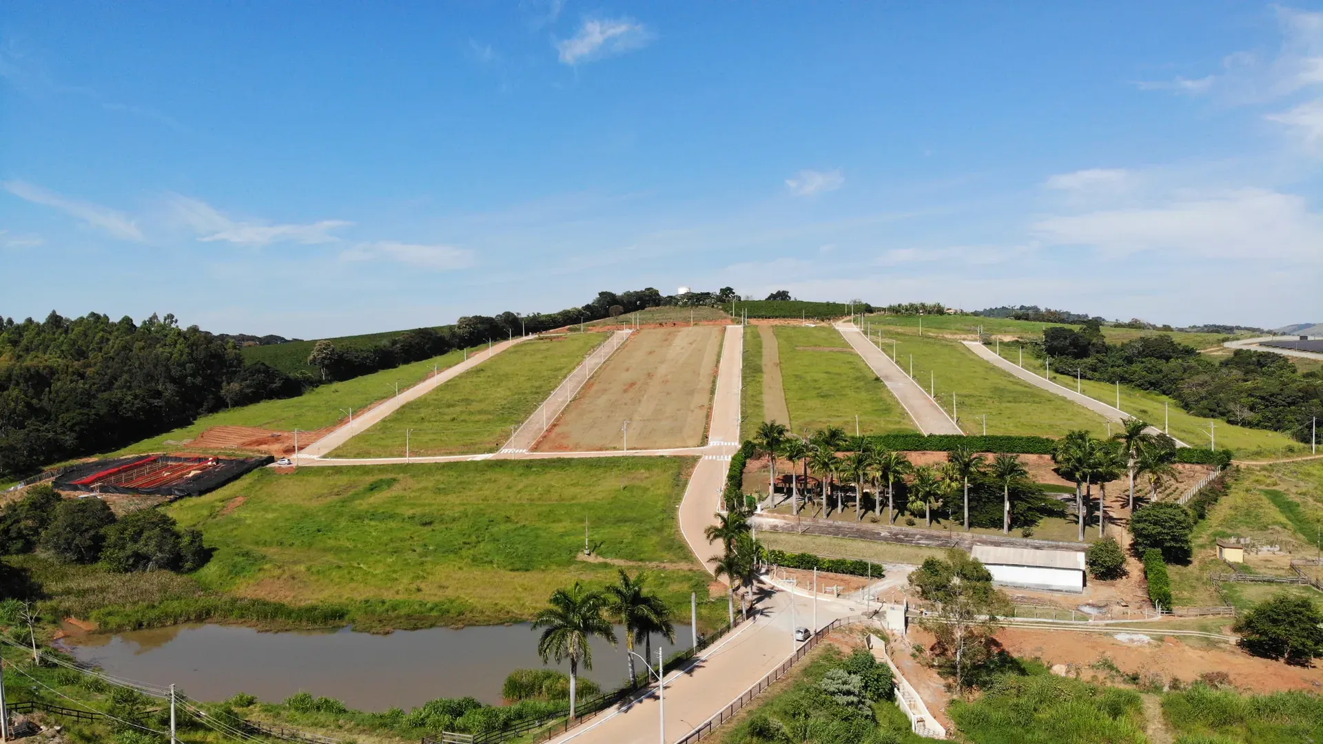 Vista aérea do Residencial Jardim Natália em Nepomuceno/MG, com os lotes demarcados do loteamento, um lago e a cidade ao fundo