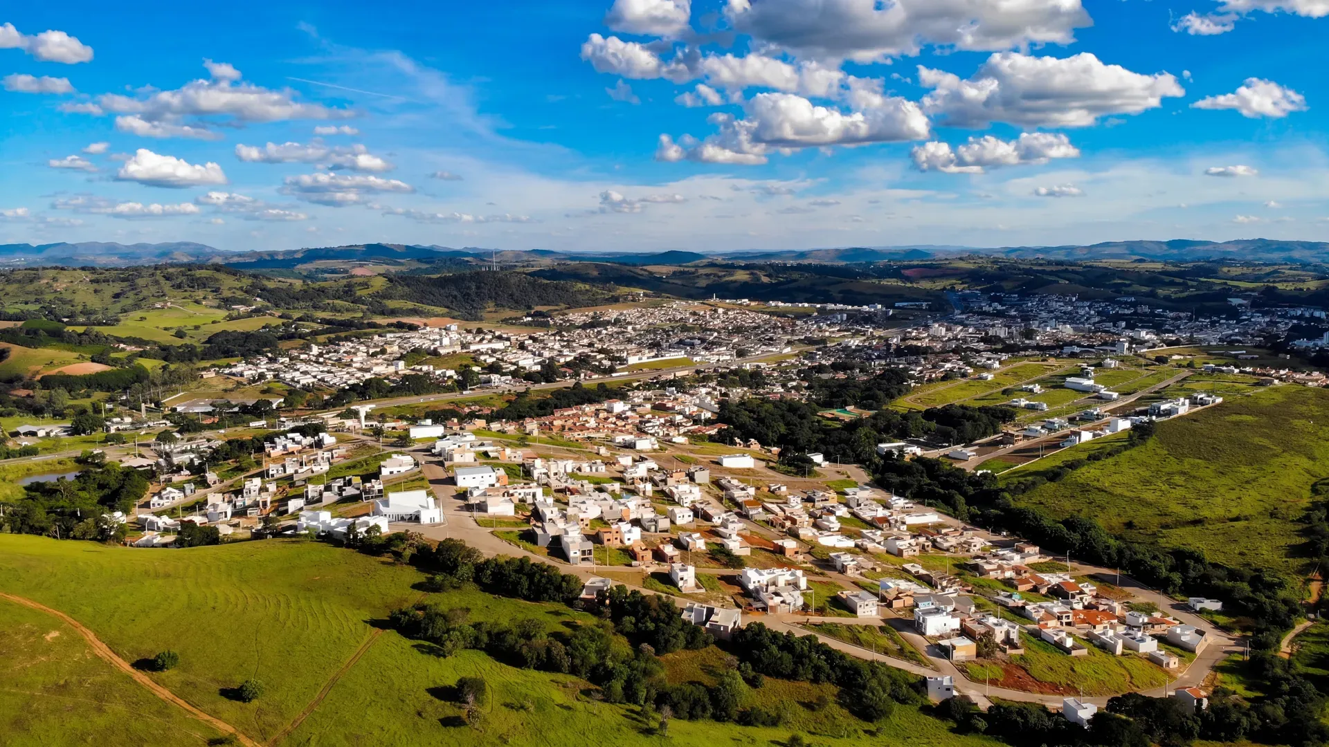 Vista aérea panorâmica do Residencial Vila Real em Perdões/MG, com casas, ruas pavimentadas e a cidade ao fundo