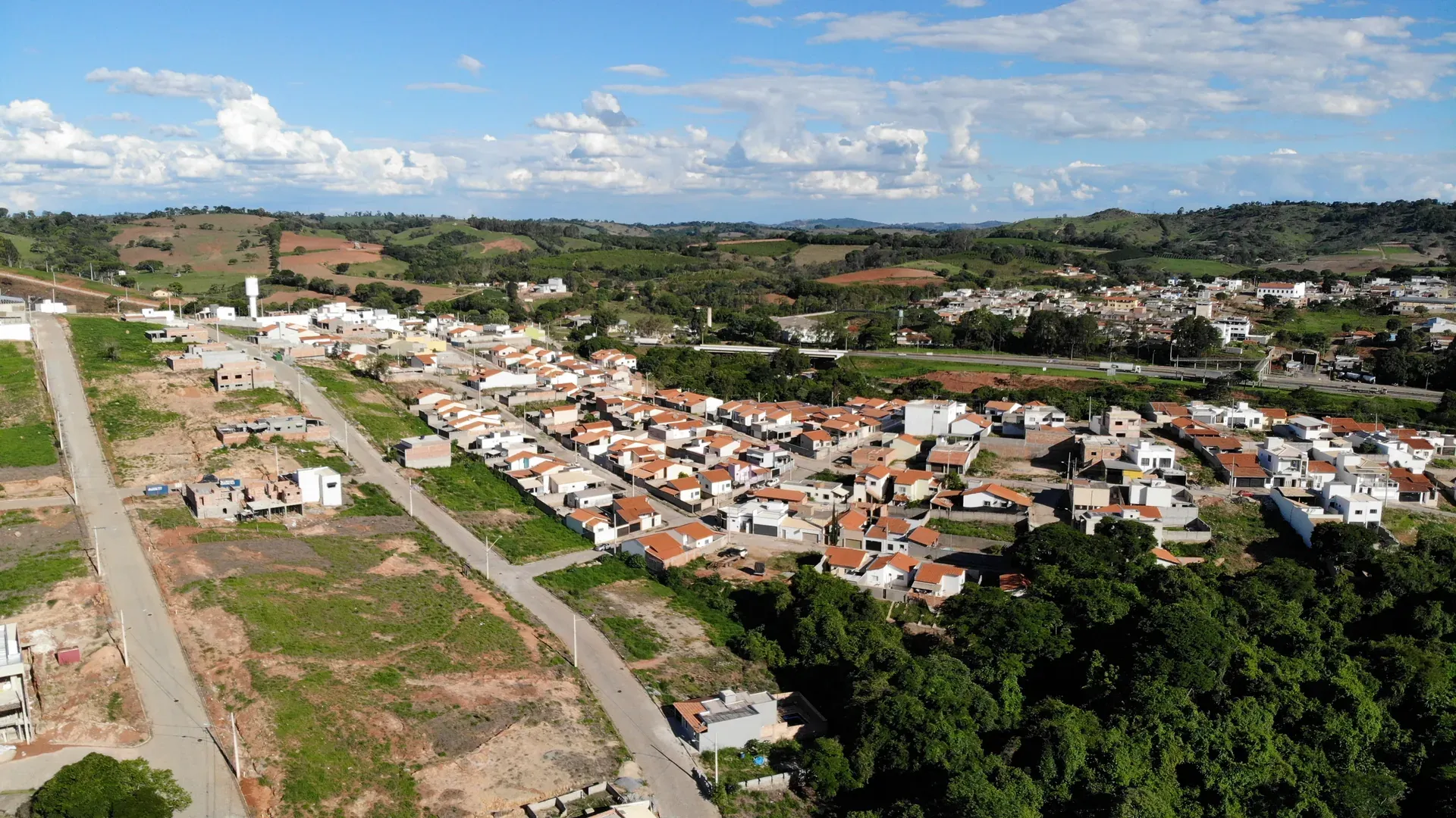 Vista aérea do Residencial Jardim Centenário em Perdões/MG, bairro consolidado com mais de 100 casas habitadas, ruas pavimentadas e a serra ao fundo