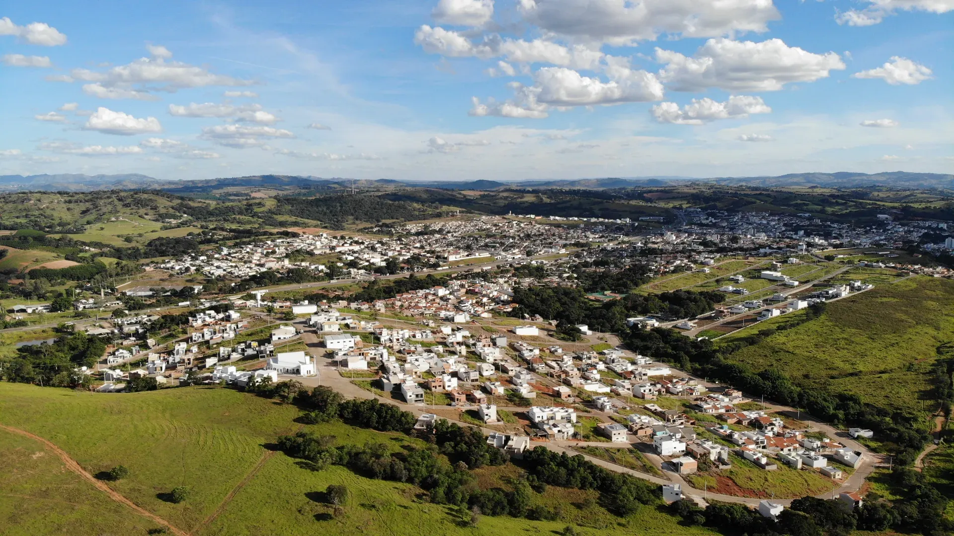 Vista aérea panorâmica do Residencial Vila Real em Perdões/MG, com casas, ruas asfaltadas e a cidade ao fundo