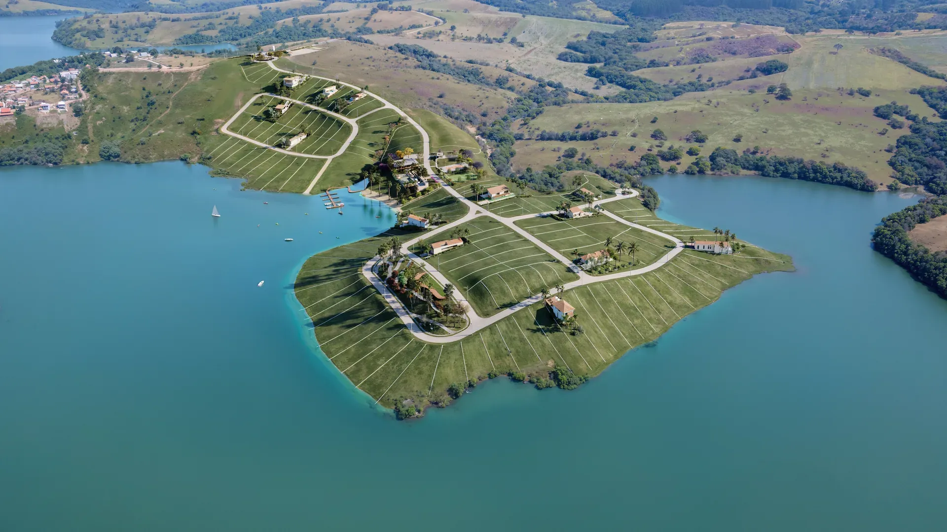 Vista aérea da península do Porto Real Condomínio Náutico cercada pelo Lago do Funil em Perdões/MG, com lotes, vias arborizadas e o Real Club