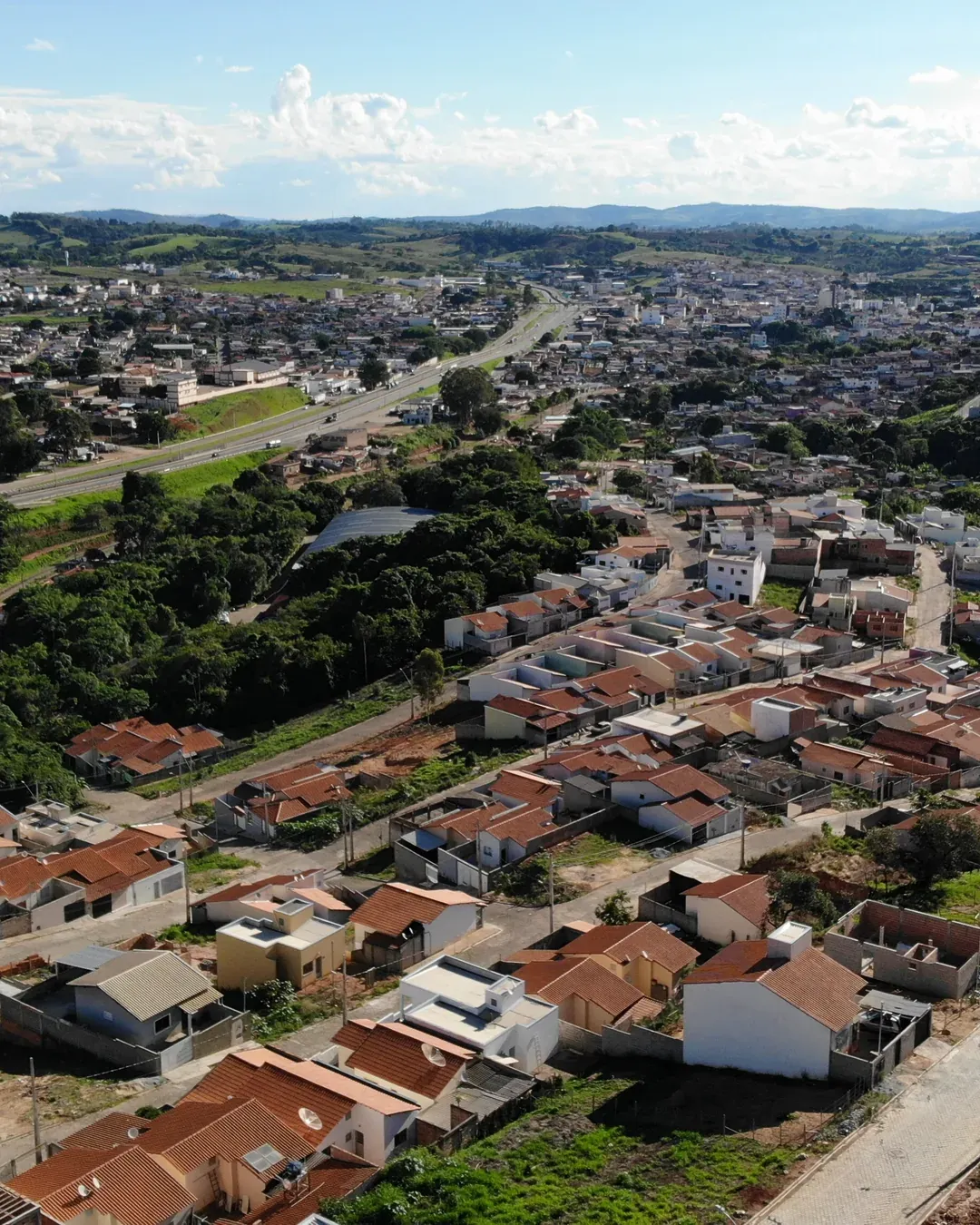 Vista aérea do Residencial Jardim Centenário em Perdões/MG — bairro consolidado com telhados, ruas pavimentadas e a cidade ao fundo, primeiro empreendimento da Real Ville.